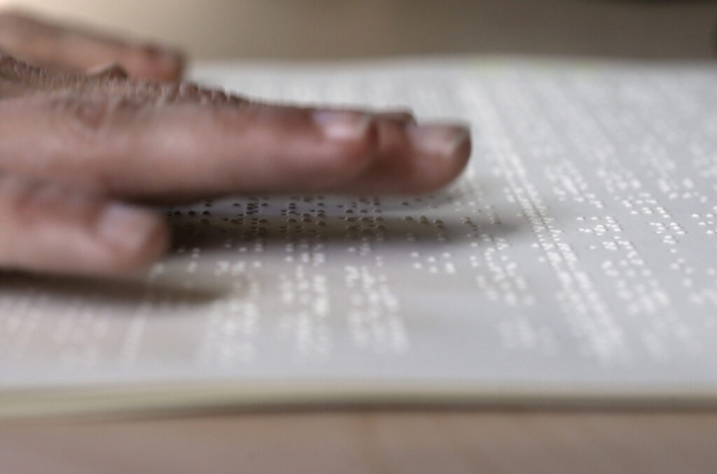 A hand runs over a page of braille.